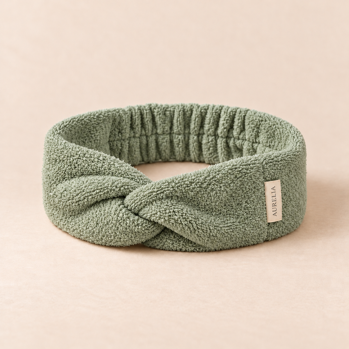 Aurelia Botanicals Spa Headband in Sage on a warm beige background.