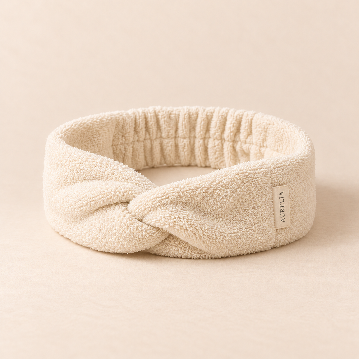 Aurelia Botanicals Spa Headband in Ivory on a warm beige background.