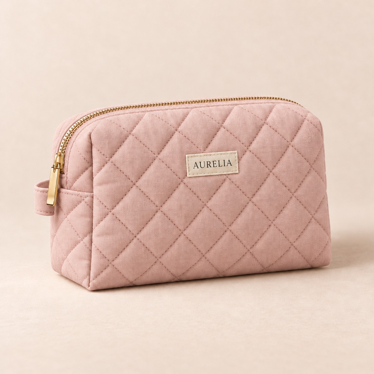 Aurelia Botanicals Quilted Cosmetic Bag in Blush on a warm beige background.