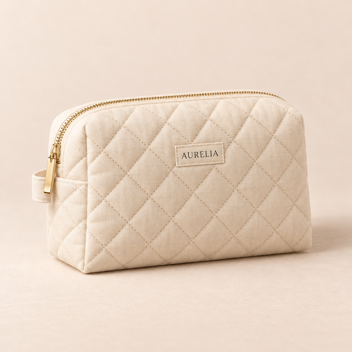 Aurelia Botanicals Quilted Cosmetic Bag in Ivory on a warm beige background.