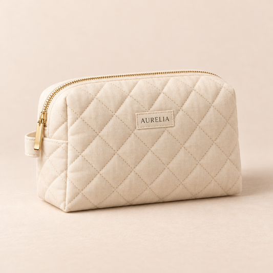Aurelia Botanicals Quilted Cosmetic Bag in Ivory on a warm beige background.